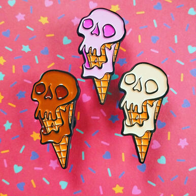 ice scream three enamel pins depicting melting ice cream cones in the shape of skulls, in strawberry, vanilla and chocolate.